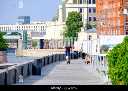 Moskau. Russland. 26. Juni 2021. Ein Mann auf einem Elektroroller fährt an einem heißen Sommertag am Ufer des Flusses Moskau entlang. Selektiver Fokus. Reisekonzept. Stockfoto