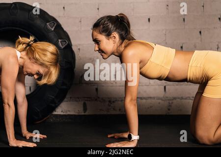 Weibliches Athletenpaar, das sich nach einem Training im Trainingsraum eines Fitnessstudios ausruhte. Anstrengung und Selbstverbesserung Stockfoto