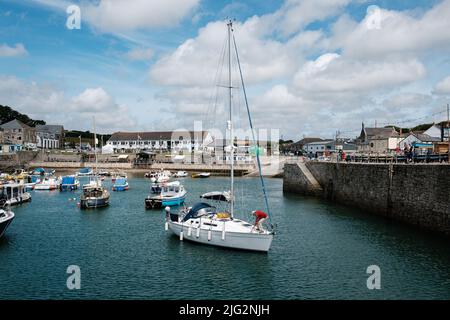 Eine zu Besuch einende Yacht liegt im Innenhafen von Porthleven, Cornwall Stockfoto