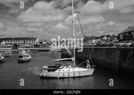 Eine zu Besuch einende Yacht liegt im Innenhafen von Porthleven, Cornwall Stockfoto