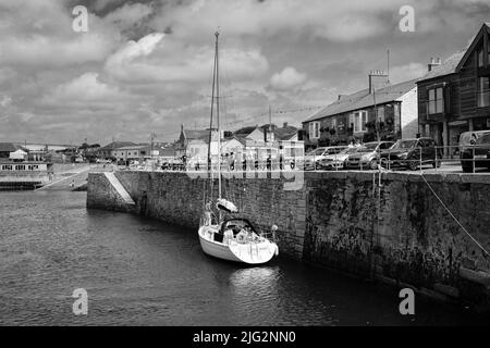 Eine zu Besuch einende Yacht liegt im Innenhafen von Porthleven, Cornwall Stockfoto