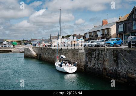 Eine zu Besuch einende Yacht liegt im Innenhafen von Porthleven, Cornwall Stockfoto