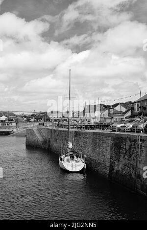 Eine zu Besuch einende Yacht liegt im Innenhafen von Porthleven, Cornwall Stockfoto