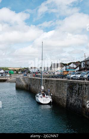 Eine zu Besuch einende Yacht liegt im Innenhafen von Porthleven, Cornwall Stockfoto