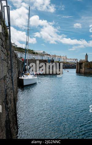 Eine zu Besuch einende Yacht liegt im Innenhafen von Porthleven, Cornwall Stockfoto