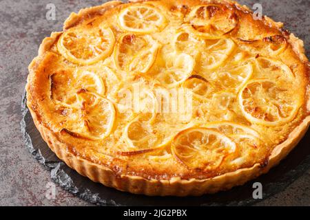 Hausgemachte süß-saure Tarte mit Zitronenruß und Fruchtstücken in Nahaufnahme auf einem Teller auf dem Tisch. Horizontal Stockfoto