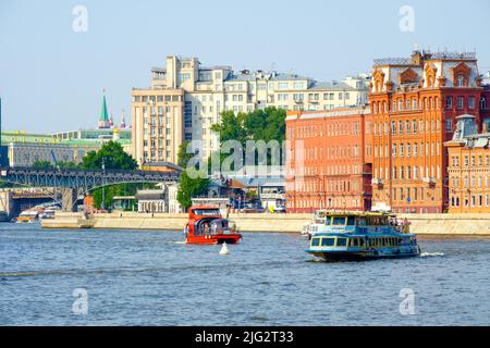 Moskau. Russland. 26. Juni 2021. Vor dem Hintergrund des Moskauer Kremls und der alten Gebäude der Fabrik des Roten Oktober segeln Vergnügungsboote entlang des Flusses Moskau. Stockfoto