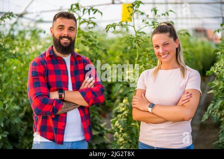 Geschäft mit organischen Treibhausgasen. Familienbauern stehen in ihrem Gemüse- und Obstgarten. Stockfoto
