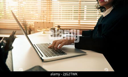 Zugeschnittenes Bild einer professionellen Rechtsanwältin, die mit Dokumenten und einem Laptop in einem hellen Büro arbeitet Stockfoto