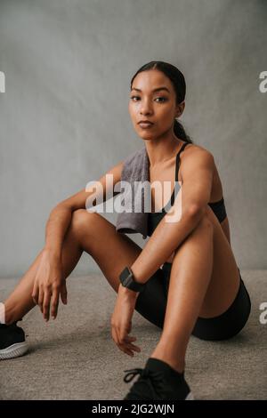 Multi Ethic Hündin sitzt auf dem Boden und wartet darauf, mit dem Work-out zu beginnen Stockfoto