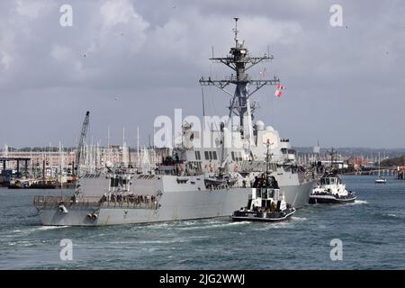 Die Schlepper, DIE NACHSICHTIG und GROSSZÜGIG sind, begleiten den von der US Navy geführten Raketenjäger USS AUF SCHWERE WEISE zu einem Liegeplatz im Marinestützpunkt Stockfoto