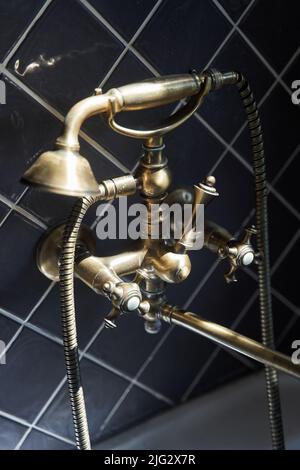 Gold Wasserhahn und Dusche alten Vintage-Stil mit grauen Fliesen Hintergrund Stockfoto