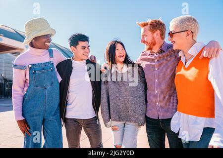 Umarmung in einer Gruppe von multikulturellen Freunden.fünf junge Menschen genießen einen sonnigen Tag. Jugendliche lachen und reden mit positiver Einstellung. Stockfoto