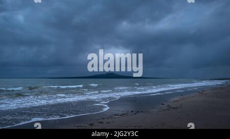 Dramatischer stürmischer Himmel über Rangitoto Island, Milford Beach, Auckland. Konzept der harten Zeit vor uns. Stockfoto