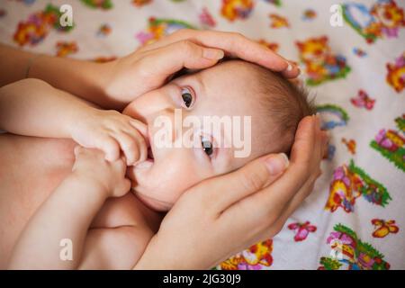 Mutter hält den Kopf ihrer neugeborenen Tochter in den Händen Stockfoto