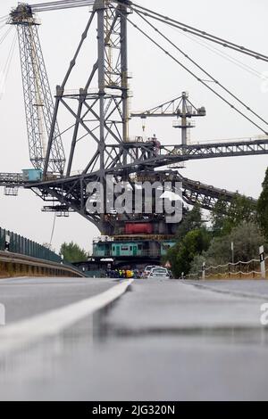 Profen, Deutschland. 07.. Juli 2022. Eine große Tagebau-Maschine fährt auf einer Straße. Der 3.800-Tonnen-Streuer wird zum Transport der Überlast im Braunkohlebergbau eingesetzt. Die 60 Meter hohe Struktur bewegt sich mit einer Geschwindigkeit von sechs Metern pro Minute. Der Grund für die Verlegung ist eine geplante Generalreparatur. Kredit: Sebastian Willnow/dpa/Alamy Live Nachrichten Stockfoto