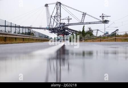 Profen, Deutschland. 07.. Juli 2022. Eine große Tagebau-Maschine fährt auf einer Straße. Der 3.800-Tonnen-Streuer wird zum Transport der Überlast im Braunkohlebergbau eingesetzt. Die 60 Meter hohe Struktur bewegt sich mit einer Geschwindigkeit von sechs Metern pro Minute. Der Grund für die Verlegung ist eine geplante Generalreparatur. Kredit: Sebastian Willnow/dpa/Alamy Live Nachrichten Stockfoto