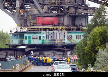 Profen, Deutschland. 07.. Juli 2022. Eine große Tagebau-Maschine fährt auf einer Straße. Der 3.800-Tonnen-Streuer wird zum Transport der Überlast im Braunkohlebergbau eingesetzt. Die 60 Meter hohe Struktur bewegt sich mit einer Geschwindigkeit von sechs Metern pro Minute. Der Grund für die Verlegung ist eine geplante Generalreparatur. Kredit: Sebastian Willnow/dpa/Alamy Live Nachrichten Stockfoto