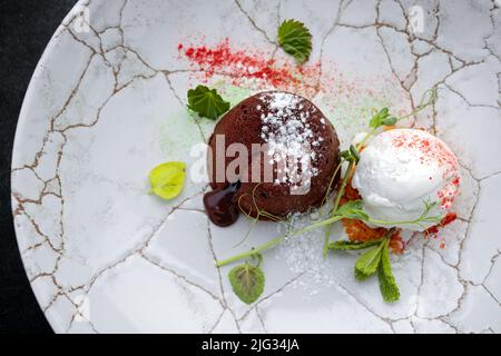 Schokoladenfondant mit Eis auf einem Teller, auf dunklem Hintergrund Stockfoto