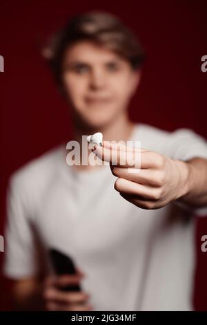 Junger Mann in weißem T-Shirt gibt moderne Kopfhörer Stockfoto