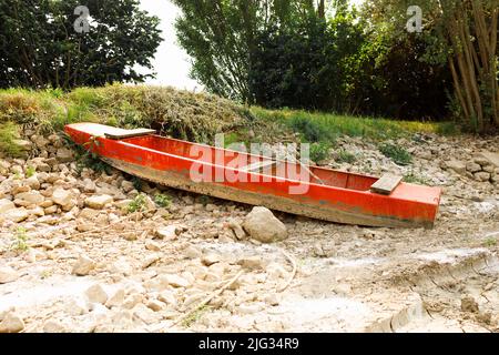 Fischerboot am Ufer eines ausgetrockneten Sees aufgrund der harten Sommerhitze und des Klimawandels Stockfoto