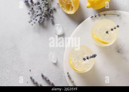Glitzernde Sommerlemonade aus Lavendel in Gläsern auf grauem Hintergrund. Blick von oben. Nahaufnahme. Stockfoto