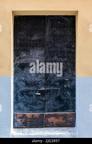 Alte Holztür und Eingang zum Metallhaus. Vor einem alten Gebäude. Eingangstür zum alten Haus. Stockfoto