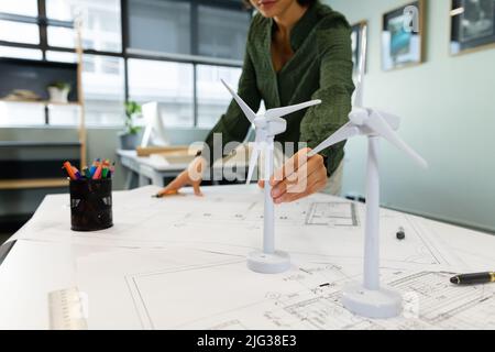 Asiatische junge Geschäftsfrau mit Windmühle Modelle am Tisch im Büro Stockfoto