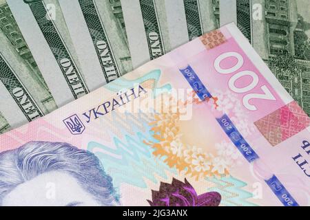 Nahaufnahme von zweihundert ukrainischen Griwna-Banknoten gegenüber einhundert Dollar-Banknoten Stockfoto