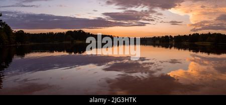 Farbenprächtiger Himmel und buntes Wasser im See spiegeln sich im Abenduntergang wider. Stockfoto
