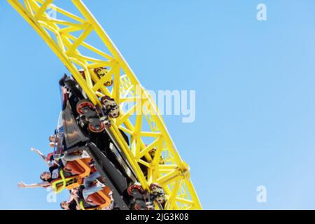 Die Menschen in der Straßenbahn fahren die Achterbahn. Extreme Attraktion im Vergnügungspark. Verschwommenes Bild. Stockfoto