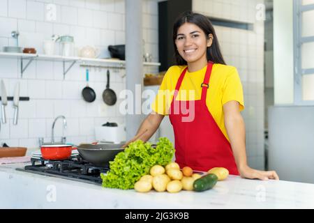 Hübsche südamerikanische Köchin bei der Arbeit in der Küche des Restaurants Stockfoto