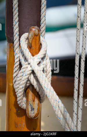 Figur der Acht-Kleckelkupplung, die einen Halyard um Einen hölzernen Kleckel auf Einem hölzernen Mast eines Segelbootes sichert, Großbritannien Stockfoto