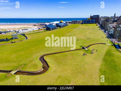 St Andrews, Schottland, Großbritannien. 7. Juli 2022. Der Old Course in St Andrews ist ein voller Aktivitäten, eine Woche vor der ersten Runde der Open Championship 150.. Mitglieder der Öffentlichkeit dürfen auf den Fairways spazieren gehen, da der Old Course ein öffentlicher Park ist. Touristen haben diesen Zugang genutzt, um neben berühmten Sehenswürdigkeiten wie der Svilken Burn-Brücke auf dem 18.-Loch-Loch-Platz für Fotos zu posieren. Bild: Luftaufnahme auf dem Fairway 18. über den Svilken Burn. Iain Masterton/Alamy Live News Stockfoto