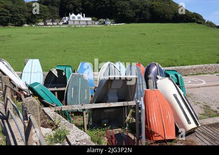 AXMOUTH, DEVON, ENGLAND - JULI 12. 2020: Umgedrehte Ruderboote am Ufer der Axe in Axmouth Stockfoto