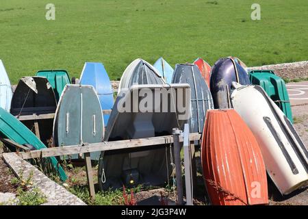 AXMOUTH, DEVON, ENGLAND - JULI 12. 2020: Umgedrehte Ruderboote am Ufer der Axe in Axmouth Stockfoto