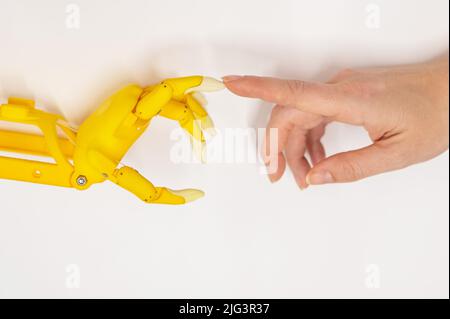 Frauenhand und eine Kunststoff-Handprothese für ein Kind auf weißem Hintergrund. Stockfoto