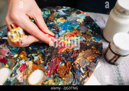 Painter mischt Farbe auf der Palette. Nahaufnahme Stockfoto