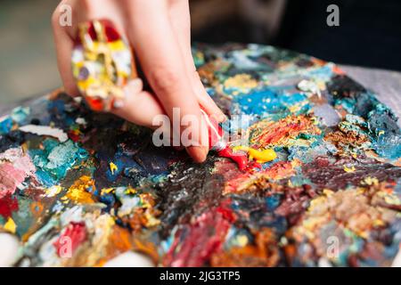 Painter mischt Farbe auf der Palette. Nahaufnahme Stockfoto