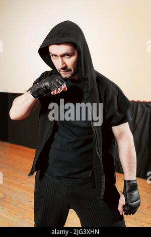 Aggressiver Straßenjäger in schwarzem Sporttuch Stockfoto