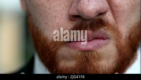 Verärgert Mann knurrende Nahaufnahme Augen und Mund. Rothaariger roter Bart grimazende wütende Person Stockfoto