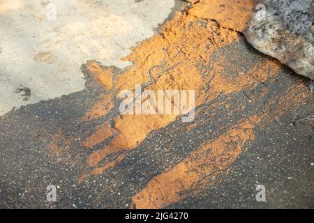 Nasser Sand auf Asphalt. Sand liegt auf dem Boden. Details der Straße. Stockfoto