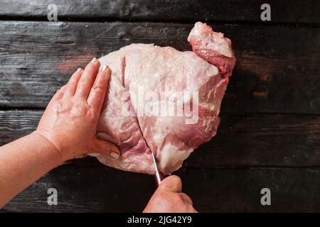 Schneiden von Schweinefleisch Stück auf Holzhintergrund Stockfoto