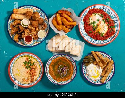 Traditionelles marokkanisches Frühstück mit frittiertem Gemüse, Halloumi, Falafel, Shakshuka, Hummus, Rotes Linsendip und Fladenbrot Stockfoto