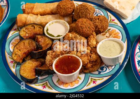 Traditionelles mediterranes arabisches warmes Frühstück mit gebratenem Blumenkohl, Auberginen, Falafel, Käserollen und verschiedenen Dips Stockfoto