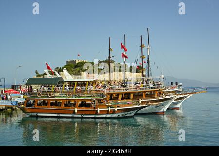 Kusadasi, Türkei - Juni Mai 2022: Touristenboote im Hafen mit Pigeon Island im Hintergrund vertäut Stockfoto