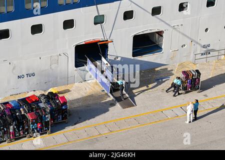 Korfu, Griechenland - Juni 2022: Besatzung entlädt das Gepäck der Passagiere im Hafen von Korfu nach dem Ende einer Kreuzfahrt um die griechischen Inseln Stockfoto