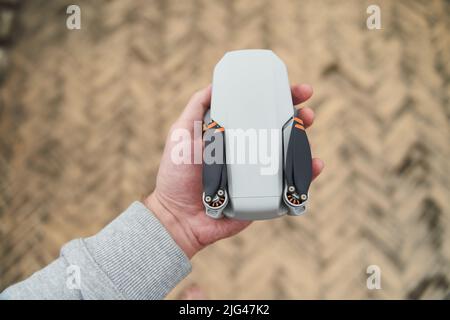 Moderner kleiner kompakter Quadcopter in der Hand eines Mannes. Starten einer Drohne von Ihrer Hand Stockfoto