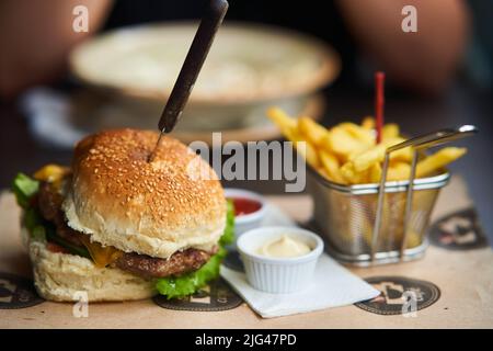 Saftiger Burger mit pommes auf einem Holztablett Stockfoto