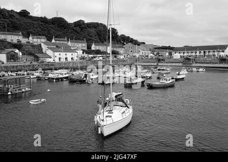 Eine Yacht, die den Hafen von Porthleven, Cornwall verlässt Stockfoto